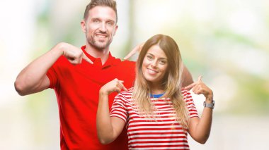 Yüzünde gülümseme ile kendinden emin görünüyorsun, kendini gururlu ve mutlu parmakları ile işaret izole arka plan üzerinde aşık genç çift.