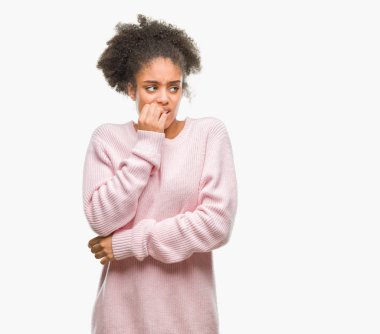 Stresli ve gergin elle çivi ısırma ağzına bakarak izole arka plan üzerinde kış kazak giyen genç afro Amerikalı kadın. Anksiyete sorunu.