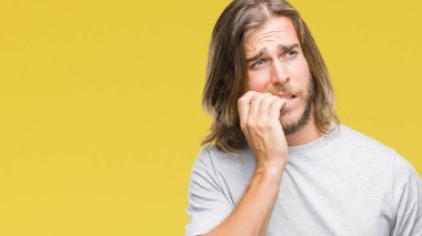 Stresli ve gergin ile izole arka plan üzerinde uzun saçlı yakışıklı delikanlı tırnak ısırma dudaklarından eller. Anksiyete sorunu.