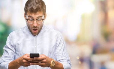 Yakışıklı delikanlı manifatura Smartphone izole arka şok sürpriz yüzü, korkuyor ve korku ifadesi ile heyecanlı olan korkmuş üzerinde kullanma