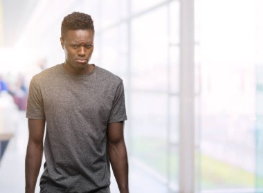 Kızgın ve korkmuş ağlıyor gri t-shirt depresif ve sıkıntı, endişe giyen genç Afro-Amerikan adam. Üzgün ifade.