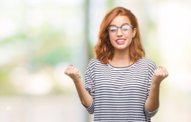 Genç güzel kadın kutluyor gözlük takan izole arka plan yüzünden şaşırttı ve silah ile başarı için yükseltilmiş ve açık gözler hayrete düşürdü. Kazanan kavramı.