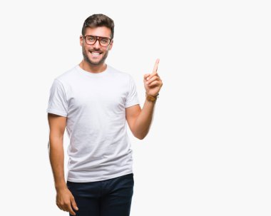 Kameraya bakarak yan el ve parmak ile işaret yüzünde kocaman bir gülümseme ile izole arka plan üzerinde gözlük takan genç yakışıklı adam.