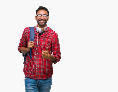 Yetişkin İspanyol öğrenci hareketi el ile mutlu yaşasın yapıyor izole arka plan üzerinde kulaklık ve sırt çantası giyen adam. Kameraya bakarak başarı gösteren ile ifade onaylama.