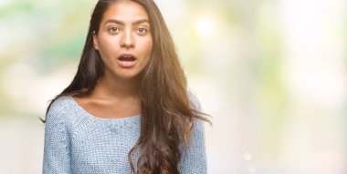 Korkuyor ve şok sürpriz ifade, korku ve heyecan yüz ile izole arka plan üzerinde kış kazak giyen genç güzel Arap kadın.