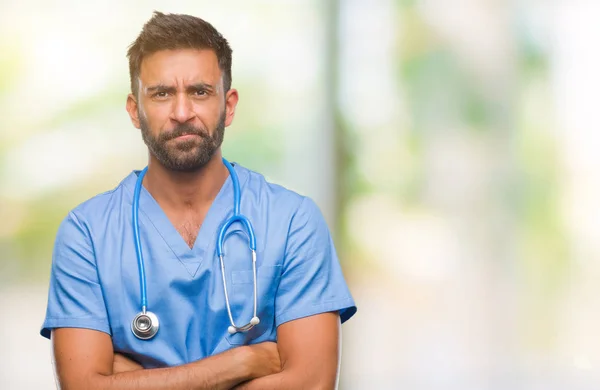 Adult hispanic doctor or surgeon man over isolated background skeptic and nervous, disapproving expression on face with crossed arms. Negative person.