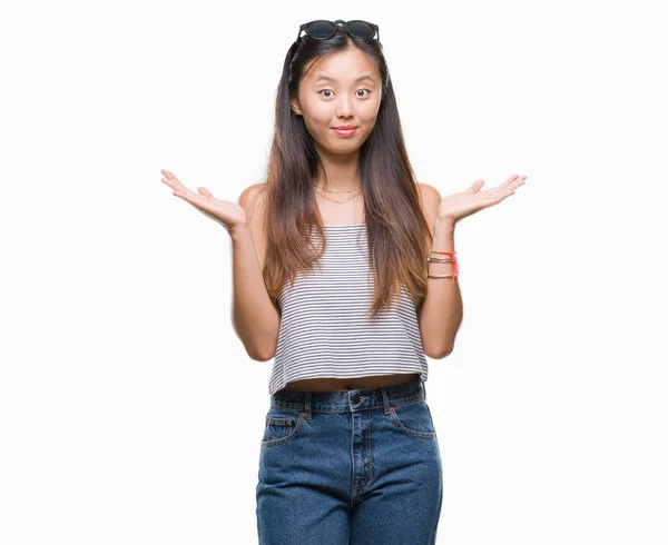 若いアジアの女性は 腕と手を上げて分離背景無知と混乱する式でサングラスをかけています 疑いのコンセプト — ストック写真