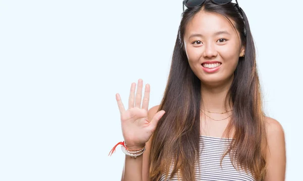 若いアジア女性のサングラス分離を示す背景と指で上向き数は自信を持って 幸せな笑みを浮かべている間 — ストック写真