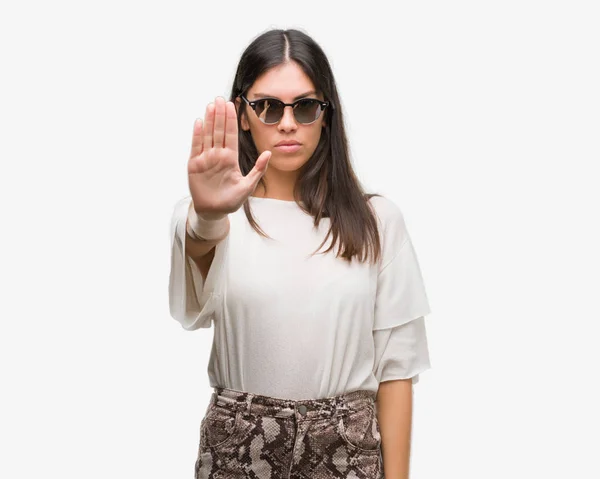 年轻漂亮的西班牙裔戴着墨镜与张开手做停止标志认真和自信的表达 防御姿态 — 图库照片