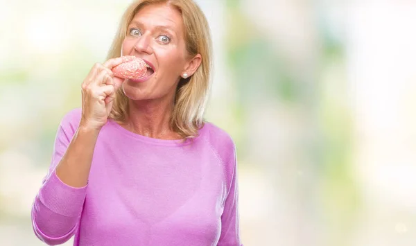 Mulher Loira Meia Idade Comendo Donut Rosa Sobre Fundo Isolado — Fotografia de Stock