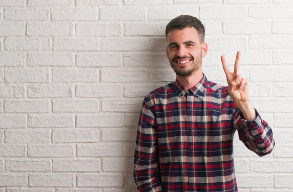 Ein Junger Erwachsener Mann Steht Lächelnd Über Einer Weißen Backsteinwand — Stockfoto