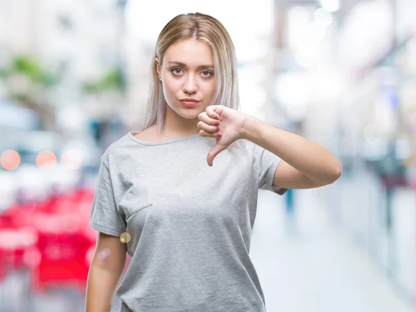 年轻的金发女人在孤立的背景看起来不高兴和愤怒显示拒绝和负面的拇指向下手势 错误的表达式 — 图库照片