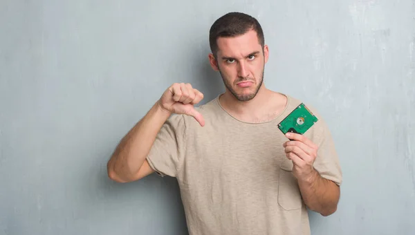 Young Caucasian Man Grey Grunge Wall Holding Hard Drive Angry — Stock Photo, Image