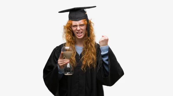 身に着けている赤毛の若い学生女性卒業怒り 狂気と怒り概念の上げられた手で叫んでの均一保持砂時計イライラと不満叫び — ストック写真