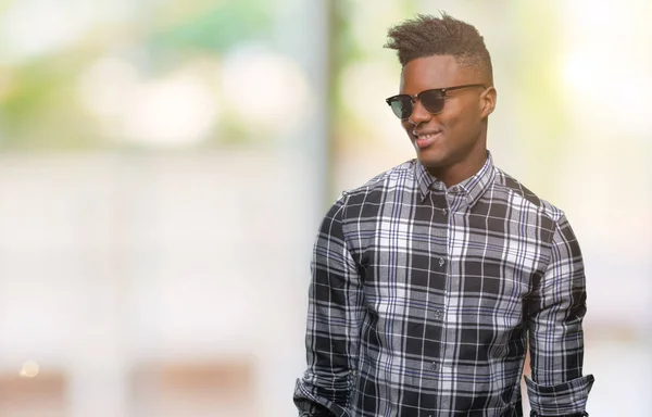年轻的非洲裔美国人戴着太阳镜在与世隔绝的背景下 脸上带着微笑 表情自然 笑的自信 — 图库照片