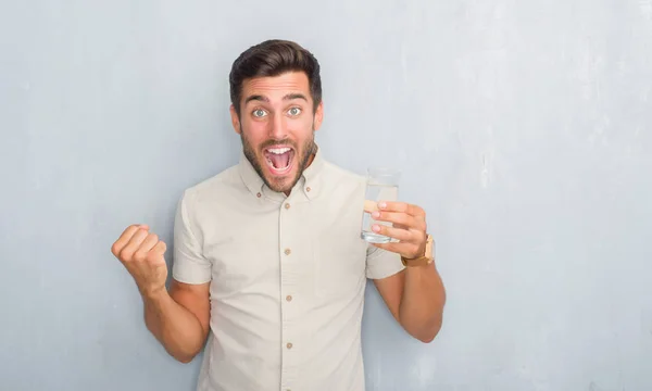 Guapo Joven Sobre Gris Grunge Pared Beber Vaso Agua Gritando —  Fotos de Stock