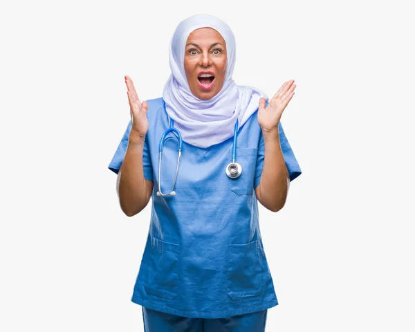 中高年シニア アラブでは 狂牛病と悲鳴上げられたとクローズの目が興奮して腕の成功のために狂気を祝う孤立の背景にヒジャーブを着ている女性看護師します 勝者の概念 — ストック写真