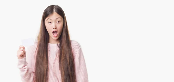 驚き顔 恐怖表現と興奮とショックで怖い訪問カードを保持している分離の背景の上の若い中国の女性 — ストック写真