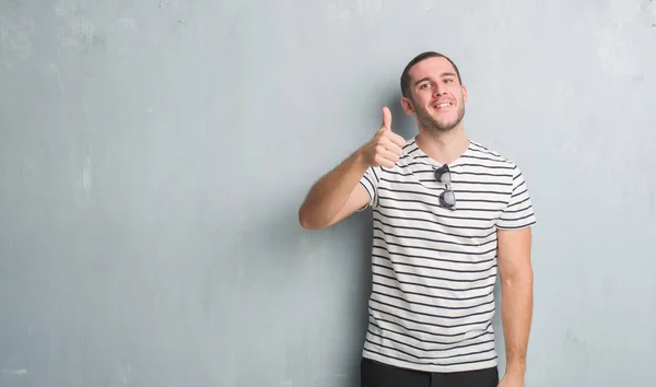 Joven Caucásico Hombre Sobre Gris Grunge Pared Haciendo Felices Pulgares —  Fotos de Stock