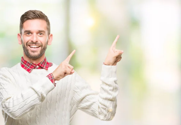 笑顔で側に つの手と指で指しているカメラを見て孤立の背景に冬のセーターを着ている若いハンサムな男 — ストック写真