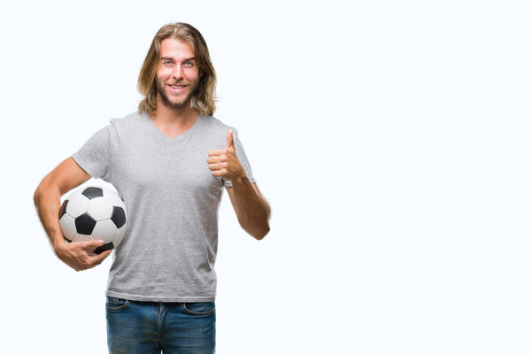 Young handsome man with long hair over isolated background holding football ball happy with big smile doing ok sign, thumb up with fingers, excellent sign