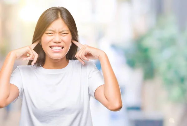 被隔绝的背景的年轻亚洲妇女在耳朵用手指以恼怒的表示为大声的音乐噪声 聋的概念 — 图库照片