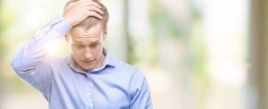 Genç yakışıklı sarışın adam kafasına, el ile vurguladı smartphone kullanarak şok utanç ve sürpriz suratla, öfkeli ve sinirli. Korku ve hata için üzgün.