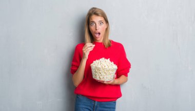 Güzel genç kadın yüzünden grunge pop Mısır bir sürpriz yüz, korkuyor ve heyecanlı korku ifadesi ile şok korkmuş yeme duvar gri