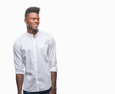 Afrikalı-Amerikalı genç uzak tarafına yüzünde, doğal ifade gülümseme ile seyir izole arka plan üzerinde. Kendine güvenen gülüyor.