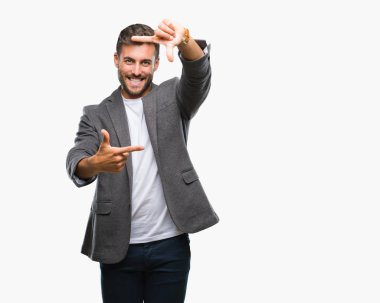 Genç yakışıklı iş adamı elle yapma çerçeve ve parmakları ile mutlu yüz gülümseyen izole arka plan üzerinde. Yaratıcılık ve Fotoğrafçılık kavramı.