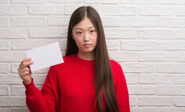 Kendinden emin bir ifade ile boş kağıt ciddi düşünme acımak yüz tutan tuğla duvarın üzerinden Genç Çinli kadın