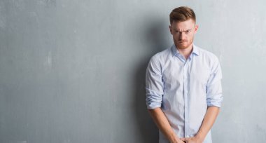 Üzerinde gri grunge duvar şüpheci ve sinir, papatyanın üzgün sorun nedeniyle genç redhead iş adamı. Negatif kişi.