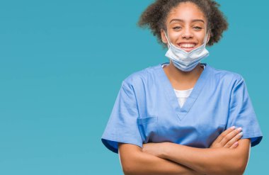 İzole arka plan mutlu yüz çapraz silah kameraya bakarak ile gülümseyen genç afro Amerikalı doktor kadın. Olumlu bir kişi.