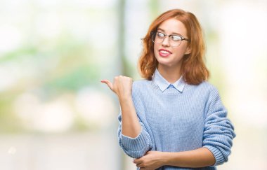 İzole arka planı arıyorum ve başparmak yanında yukarıyı mutlu yüz ile gülümseyen kış kazak giyen genç güzel kadın.