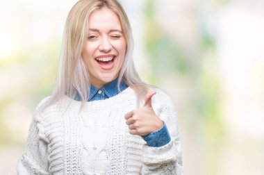 Sarışın genç kadın hareketi el ile mutlu yaşasın yapıyor izole arka plan üzerinde kış kazak giyiyor. Kameraya bakarak başarı gösteren ile ifade onaylama.