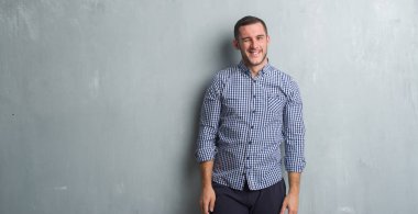 Gri grunge duvar seksi bir ifadeyle, neşeli ve mutlu yüzünü kameraya bakarak göz kırpıyor üzerinde beyaz delikanlı.