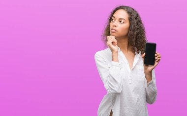 Fikir Smartphone ciddi bir yüz düşünme soru hakkında çok kullanan genç İspanyol kadın karışık