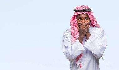 Geleneksel keffiyeh üzerinde giyen genç Arapça Afrika adam arka plan ağız hata için elleriyle kapsayan şok izole. Gizli kavramı.