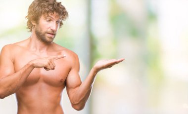 Yakışıklı İspanyol modeli adam seksi ve gömleksiz üzerinden hayran ve el ile sunulması ve parmak ile işaret ederken kameraya gülümseyen izole arka plan.