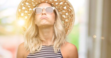 Genç kadın güneş gözlüğü yaz şapka uykulu ifade, çok çalıştırılıyordu ve yorgun ile kullanma