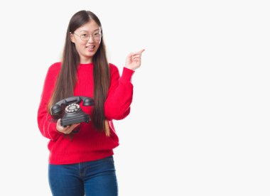 Genç Çinli kadın vintage telefon çok mutlu el ve parmak ile tarafına işaret tutan izole arka plan üzerinde