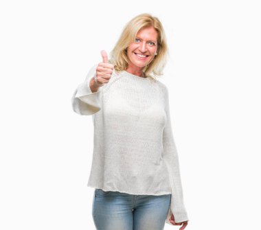 Kış kazak giyen orta yaş sarışın kadın hareketi el ile mutlu yaşasın yapıyor arka plan izole. Kameraya bakarak başarı gösteren ile ifade onaylama.