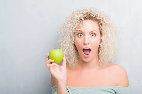 Jonge Blonde Vrouw Grunge Achtergrond Eten Groene Appel Bang Schok — Stockfoto