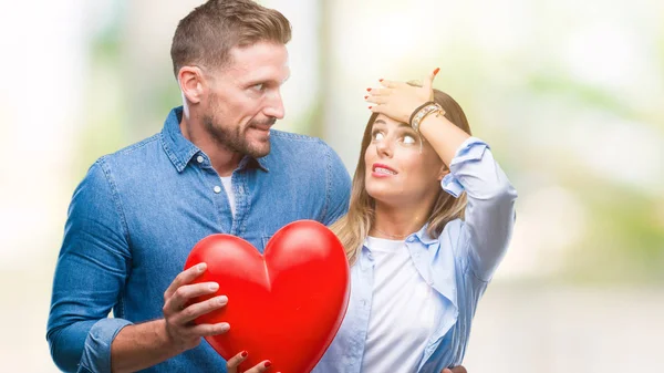 Jovem Casal Apaixonado Segurando Coração Vermelho Sobre Fundo Isolado Estressado — Fotografia de Stock