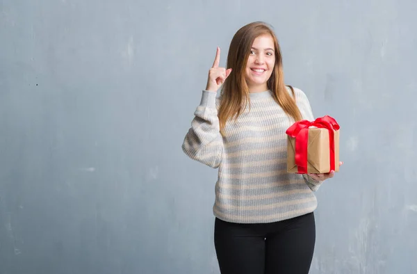 Young Adult Woman Grey Grunge Wall Holding Present Surprised Idea — Stock Photo, Image