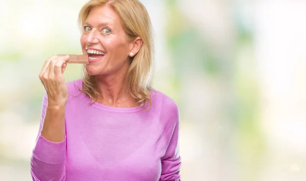 Middle Age Blonde Woman Eating Chocolate Bar Isolated Background Confident — Stock Photo, Image