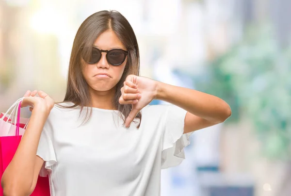 怒った顔 ダウン親指で嫌悪感を示すマイナス記号 拒絶反応の概念と分離の背景の上販売の買い物袋を保持している若いアジア女性 — ストック写真