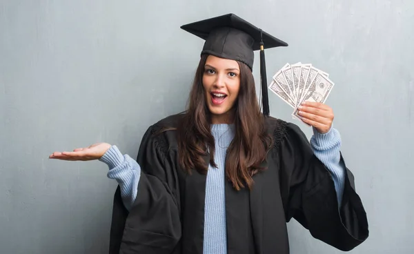 Joven Morena Sobre Pared Gris Grunge Vistiendo Uniforme Graduado Sosteniendo — Foto de Stock