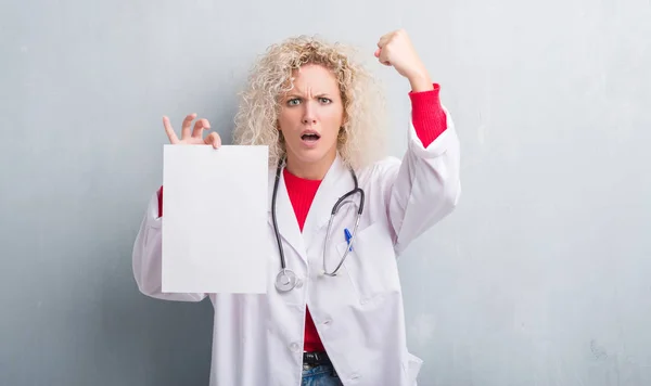 グランジ グレイ以上の金髪女医女性壁腹空白の紙のシートを保持しているとイライラ叫び狂気と上げられた手で 叫んで 怒りと怒りの概念 — ストック写真