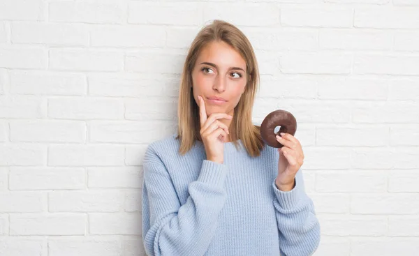 Beyaz Tuğla Duvar Yeme Üzerinde Güzel Genç Kadın Çikolatalı Çörek — Stok fotoğraf